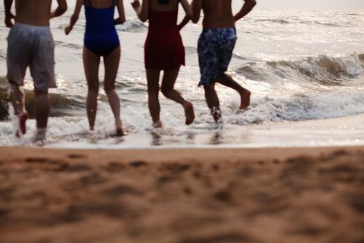Four friends running into the water on a sandy beach, Silhouette