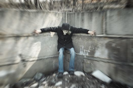 Human in the gas mask standing in the concrete corner. Artistic zoom blur added during shooting