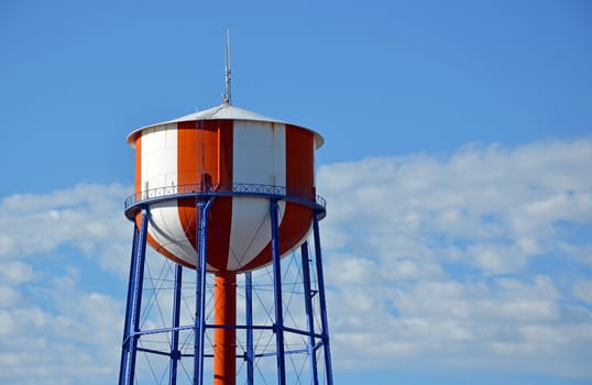 Red and white striped water tower against blue sky