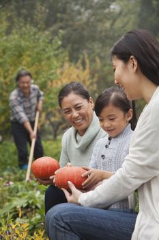 Happy family harvesting vegetables in garden