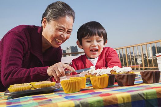 Grandmother and grandson decorating cupcakes 