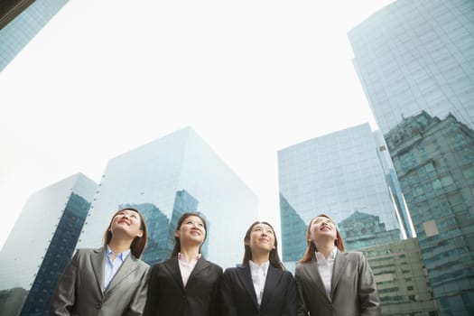 Group of young businesswomen standing in a row among skyscrapers, Beijing