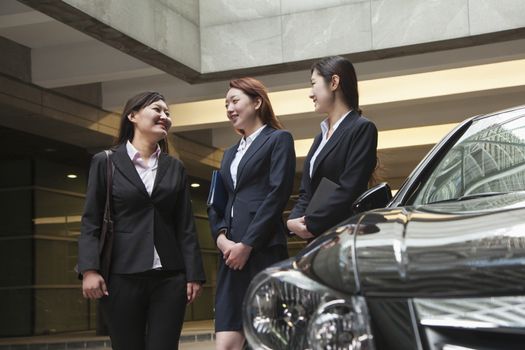 Three young businesswomen meeting and talking in parking garage