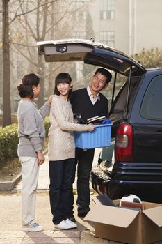 Family unpacking minivan for college, Beijing