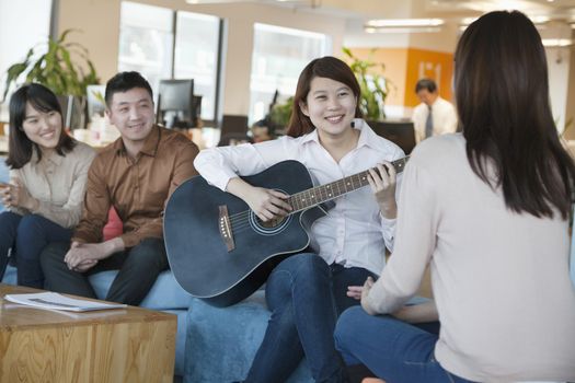 Young Office Worker Playing Guitar to Colleagues