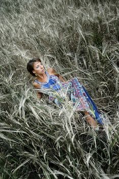 Photo of the lady in blue dress laying and resting in the meadow