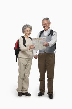Senior couple with backpacks checking map