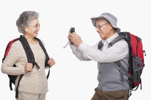 Senior man taking wife's picture with digital camera