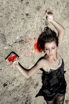 Lady laying on a desert ground and killing herself by the stone