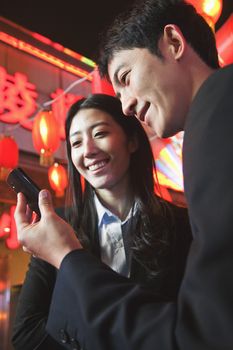 Coworkers using smart phone at night, City street, red lanterns on the background