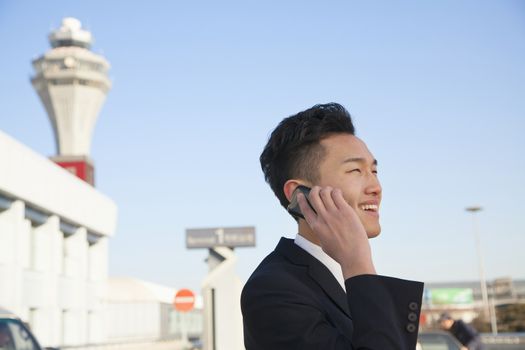 Traveler talking on cellphone outside at airport