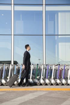 Traveler with suitcase next to row of luggage carts at airport