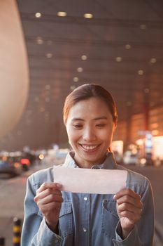 Young traveler looking at ticket at airport