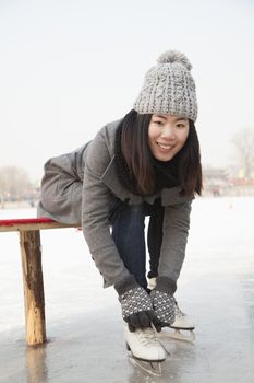 Young woman putting on ice skate, Beijing