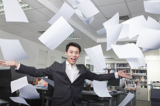 White-collar worker throwing white sheets in air in office