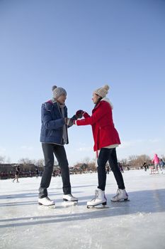 Young couple skating at ice rink