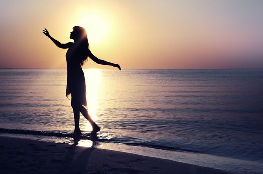 Silhouette of the woman at the beach during sunset. Natural light and colors