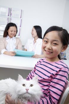 Woman and girl with pet dog in veterinarian's office