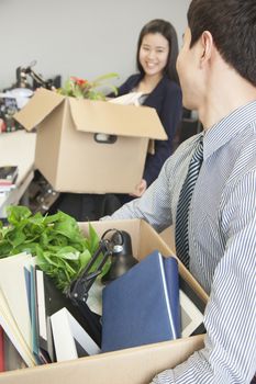 Two young business people carrying boxes with office items