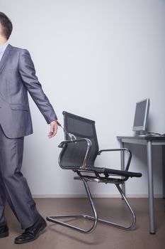 Businessman handcuffed to his office chair, walking away