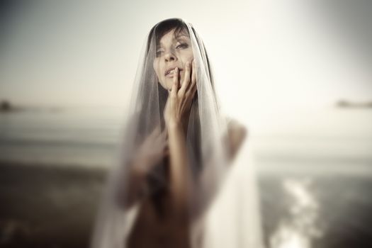 Bizarre wedding photo of the single bridal witch outdoors. Shallow depth of field added by the tilt lens. Artistic colors and grain added