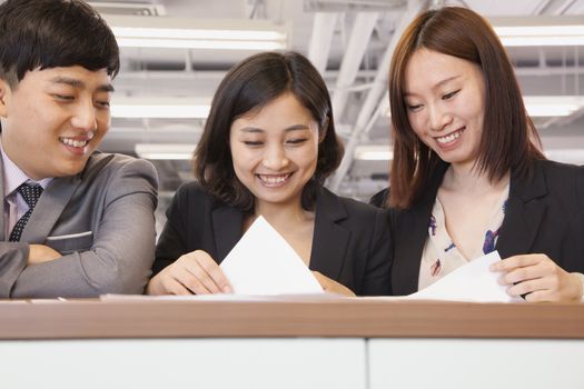 Office workers working together, looking at documents 