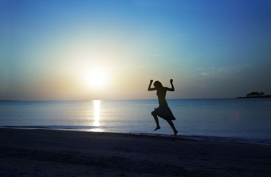 Happy topless lady running along the beach during sunset. Natural darkness and colors