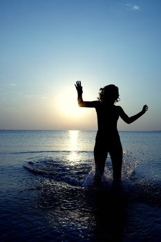 Silhouette of the woman running and playing in the sea