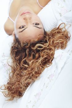 Sexy lady with curly hairs laying on the bed. Close-up portrait