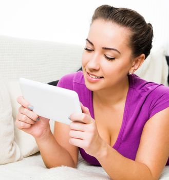 Young girl reading tablet pc on the sofa.