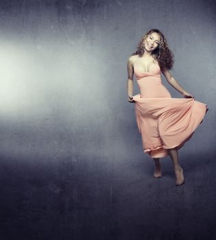 Smiling lady dancing indoors on a trash background