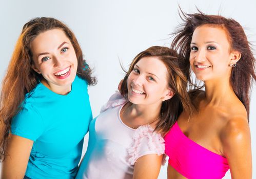 three beautiful teenage girls smiling on light background