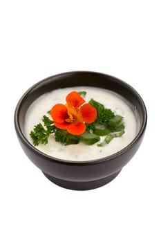 Bowl of white sauce with chives, parsley and orange flower isolated on white background.