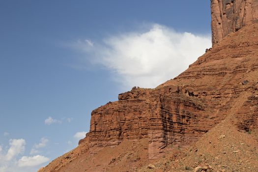 Rugged, sandstone ridges against a blue sky with windswept, white clouds.  The La Sal Mountains, south of Moab, Utah, are part of Manti-La Sal National Forest.  With heights of nearly 13,000 feet, the alpine LaSal Mountains are an outdoor recreational and tourist attraction.   