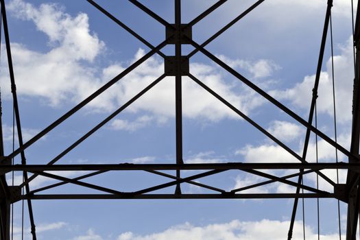 Structural geometry of steel cables of Utah’s Dewey Bridge, a famed, historic suspension bridge listed in the National Historic Register, was built across the Colorado River in 1916 and partially destroyed by fire in 2008. Copy space with image taken against background of blue skies and white clouds. Remains of bridge are on scenic  Rt. 128. 