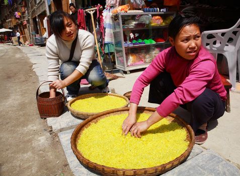 GUIZHOU PROVINCE, CHINA - APRIL 8: Dong ethnic women treated with rice on a street Zhaoxing Dong Village, Southwest China, April 8, 2010. Zhaoxing Town, Liping County, Guizhou, China.