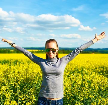 Girl with outstretched arms at colza field