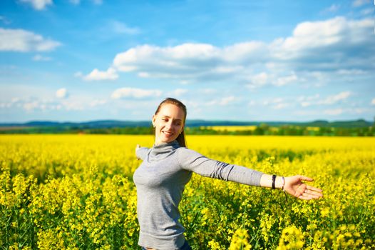 Girl with outstretched arms at colza field