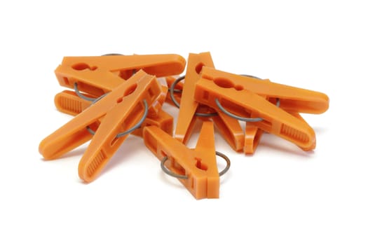 Orange plastic clothespins on white background