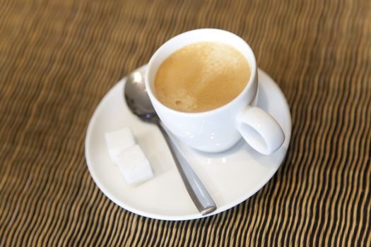 Espresso cup in a restaurant table with sugar and spoon