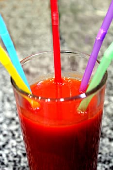 image of glass of tomato juice with multi-coloured tubules