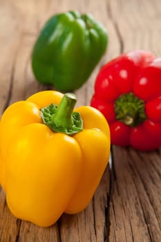 three sweet peppers, wooden table background