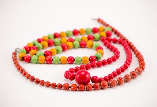 handmade wooden necklace made of small round colorful pieces beads on white background. simple jewelry apparel.