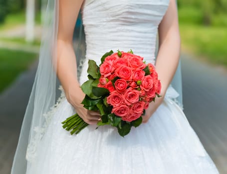Beautiful wedding bouquet in the hands of the bride in a park