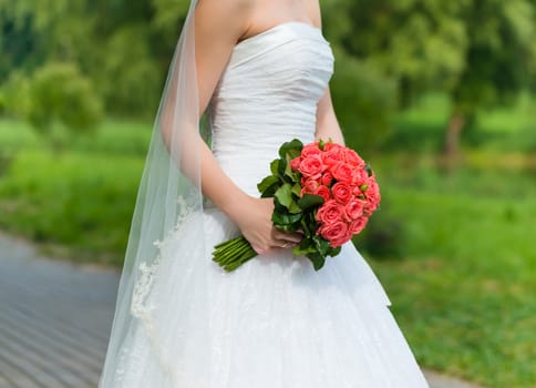 Beautiful wedding bouquet in the hands of the bride in a park