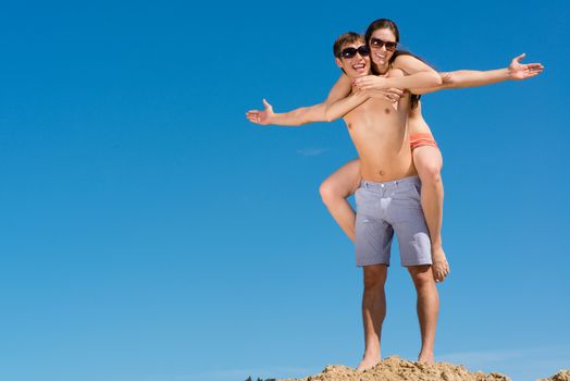 Young couple hugging on a background of blue sky, hold together honeymoon