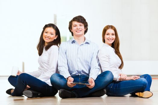 portrait of a group of young people sitting on the floor, man and two attractive women