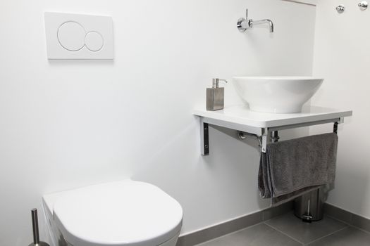Modern bathroom interior with a wall mounted tap and ceramic hand basin and toilet