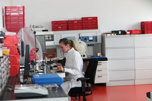 Attractive female laboratory technician seated at a counter working in a modern laboratory