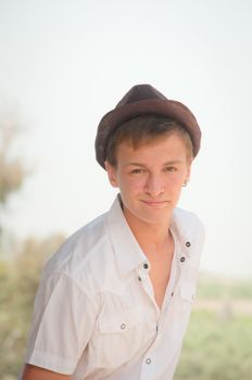 Portrait of a teenager in a white shirt and a brown hat.